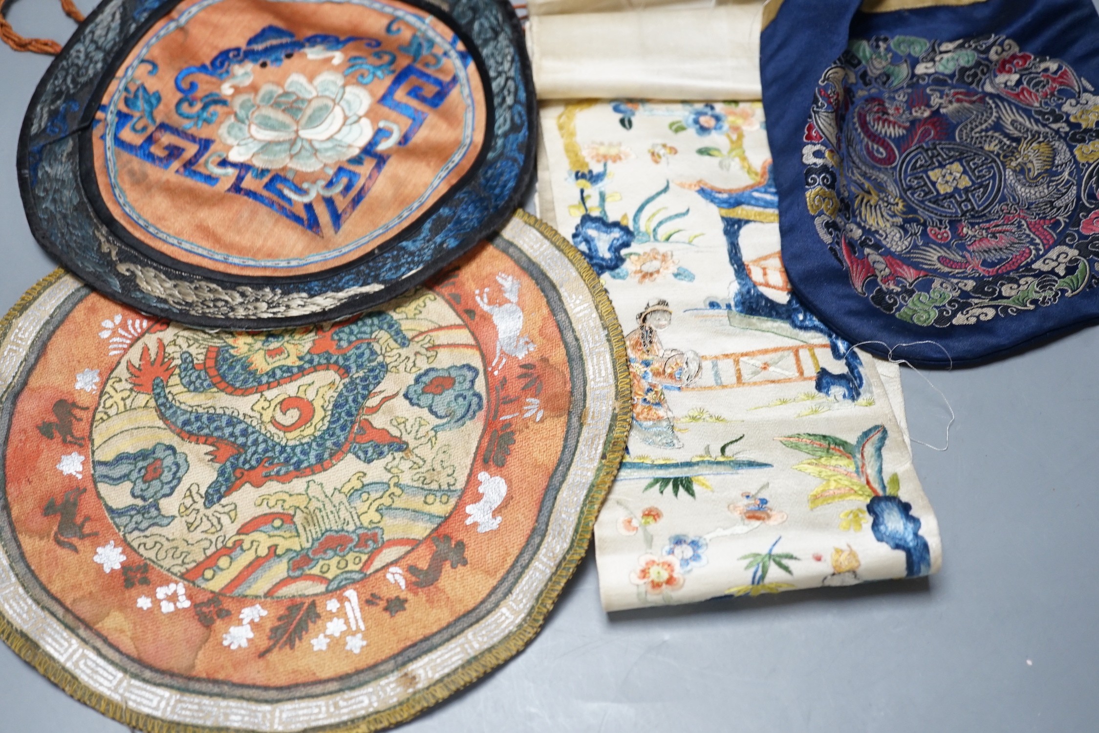 A Chinese embroidered sleeve band, two mats and a woven brocade bag.